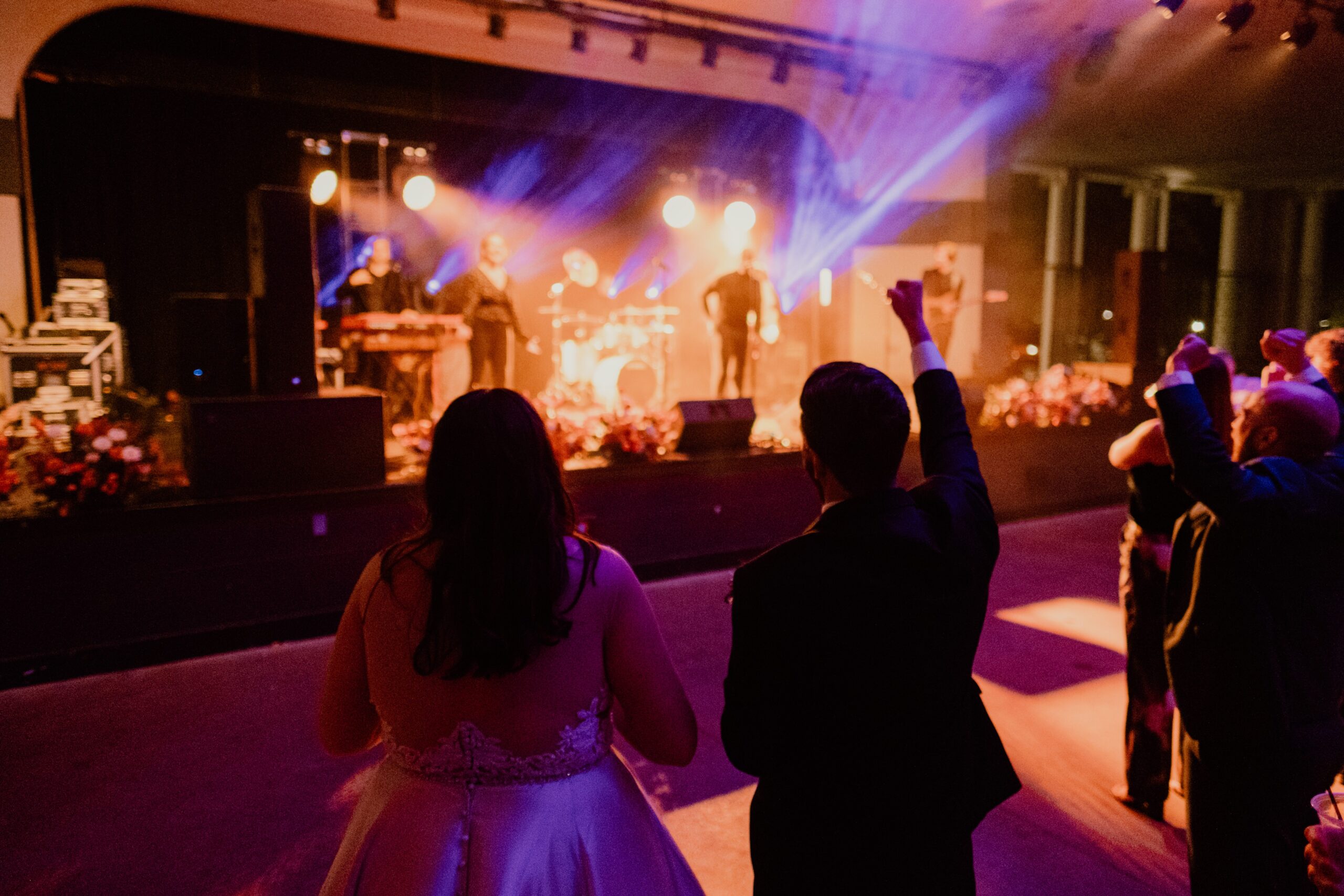 a bride and groom celebrate with a live band facing a stage at the como lake pavilion, wedding