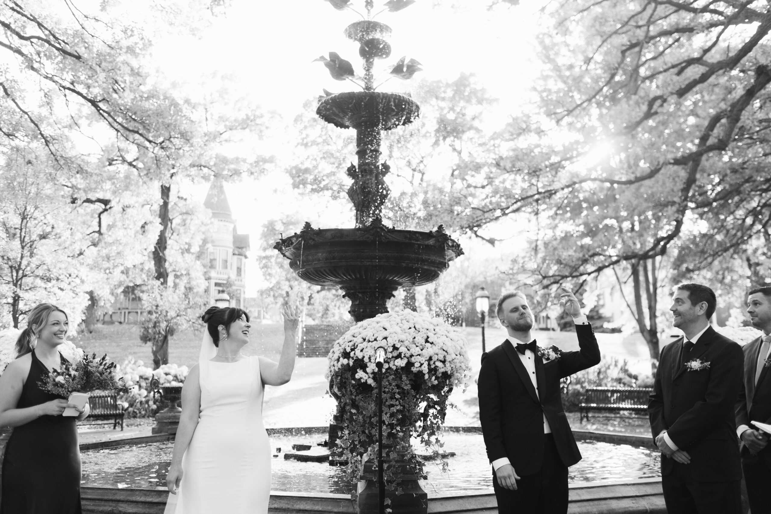 couple tosses coin into fountain during wedding ceremony at irvine park